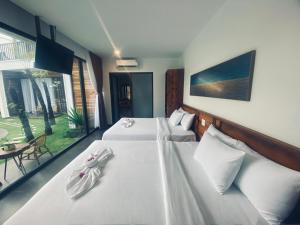 ムイネーにあるTuong Vy Boutique Hotel Mui Neのホテルルーム 白いシーツ付きのベッド2台付