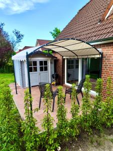 - une terrasse avec 2 chaises et un parasol dans l'établissement Ferienwohnung an der Nordsee, à Emden