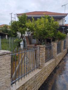 una valla frente a una casa con árboles en Traditional Stone House-Ideal for families, en Archea Pissa