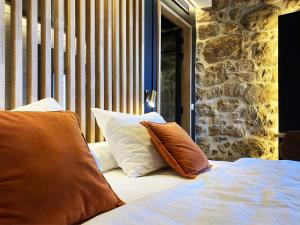 un letto con due cuscini sopra accanto a un muro di pietra di Pou by Seaward Suites Only Adults a Villajoyosa