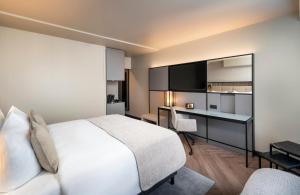 um quarto de hotel com uma cama e uma secretária com um computador em Leonardo Royal Hotel Frankfurt em Frankfurt am Main