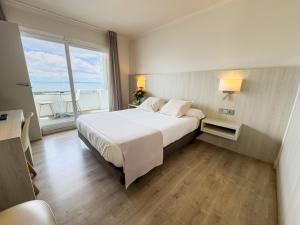 a bedroom with a large white bed with a large window at Hotel Marina in Roses