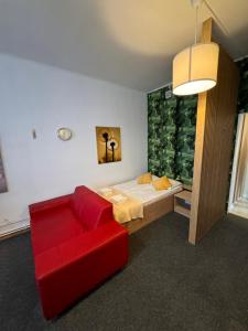 - un salon avec un canapé rouge et un lit dans l'établissement Apartamenty Stary Rynek 18, à Łomża