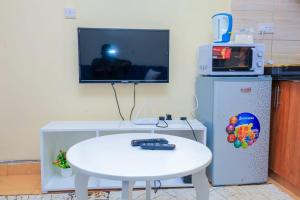 a room with a table and a tv and a white table and a small table at Sunlit Furnished Studio, Kisii in Kisii