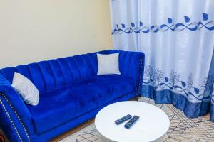 a blue couch and a table in a living room at Sunlit Furnished Studio, Kisii in Kisii