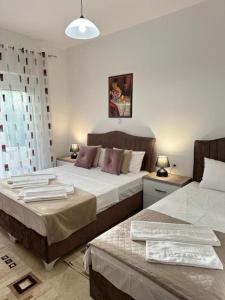 two beds in a bedroom with two tables at Apartments Sija in Ulcinj