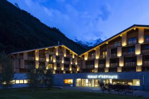 ein Hotelgebäude mit Bergen im Hintergrund in der Unterkunft Appartements de l'Héliopic in Chamonix-Mont-Blanc