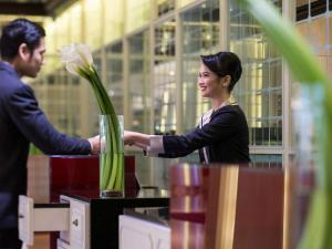 Ein Mann und eine Frau mit einer Vase voller Blumen in der Unterkunft Pullman Jakarta Indonesia in Jakarta