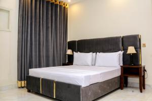 1 dormitorio con 1 cama grande y cabecero negro en Royalton INN Liberty, en Lahore