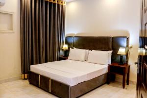 1 dormitorio con 1 cama grande y cabecero de madera en Royalton INN Liberty, en Lahore