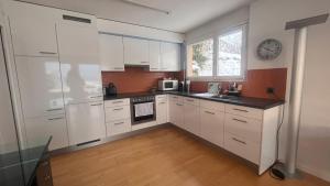 a kitchen with white cabinets and a clock on the wall at Swiss Paradise Weggis in Weggis