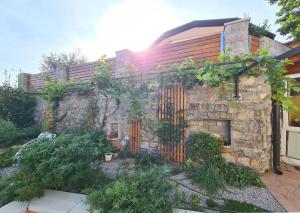 um jardim com uma parede de pedra e uma cerca em Hisa idej em Sežana