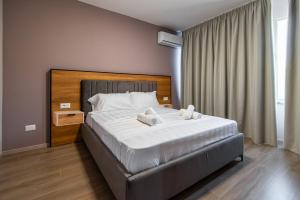 una camera da letto con un grande letto con lenzuola bianche di ApartHotel EDA a Durrës