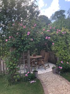 um jardim com uma mesa e um arbusto com rosas rosas em Riverside Lodge em Chablis