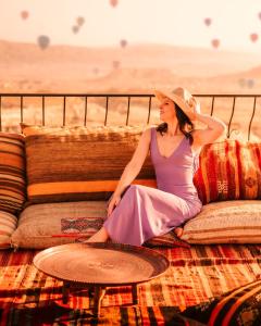 Eine Frau in einem lila Kleid und Hut auf einer Couch in der Unterkunft Ages in Cappadocia in Uchisar