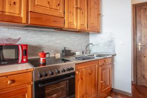 a kitchen with wooden cabinets and a stove and a microwave at Marcolski home in Breuil-Cervinia