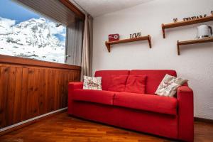 a red couch in a room with a snow covered mountain at Marcolski home in Breuil-Cervinia