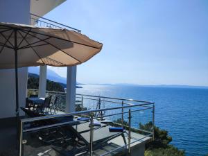 a balcony of a house with an umbrella and the ocean at Villa Orada in Brela