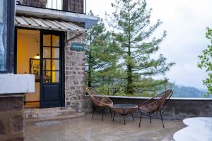 two chairs and a table on a patio with a tree at LOKAL Rooms x Murree Kashmir Point in Murree