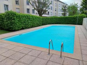 una grande piscina blu di fronte a un edificio di L'Aquarelle - Appartement cosy, GroupamaStadium LDLC Arena a Meyzieu