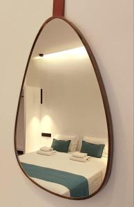 a mirror hanging on a wall with a bed at Rigas Hotel Skopelos in Skopelos Town