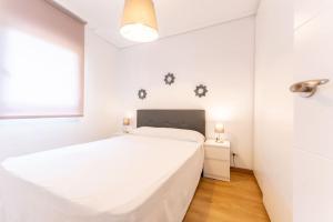 een witte slaapkamer met een bed en een raam bij luminoso apartamento en maliaño in Maliaño