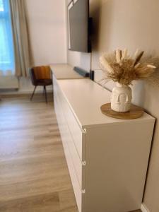 a white counter with a vase with feathers in it at 371living, Altbau-Charme am Kaßberg, Perfekt für Workation, Urlaub oder Kurztrip, Entdecke Chemnitz, Moderne Küche, Waschmaschine, Smart TV, Schnelles WLAN, Bequemes Bett in Chemnitz