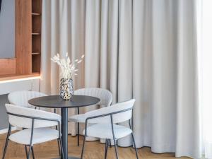 a table with chairs and a vase of flowers at Townhome Hotel Hannover - Digital Access - kontaktloser Check-in in Hannover