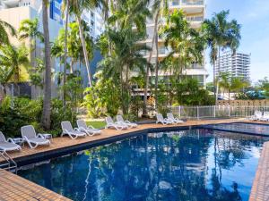 uma piscina com espreguiçadeiras e palmeiras em Hilton Garden Inn Darwin em Darwin