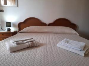 een wit bed met twee handdoeken erop bij B&B ANXUR in Terracina