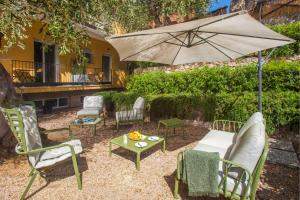 une terrasse avec des chaises, une table et un parasol dans l'établissement 0.8 Guest House, à Porto Ercole