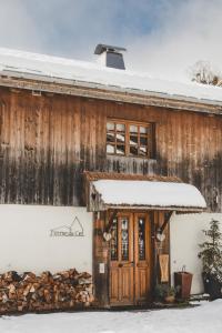 een oud houten huis met sneeuw op het dak bij Ferme du Ciel in Samoëns