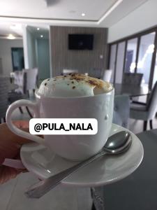 a person holding a cup of coffee on a saucer at PULA NALA LODGE in Rustenburg