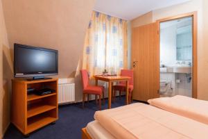 Cette chambre dispose d'une télévision et d'une table avec des chaises. dans l'établissement Stumbergers Hotel, à Cochem