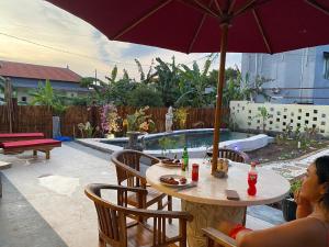 a woman sitting at a table with an umbrella at Villa NiMo Jimbaran in Jimbaran