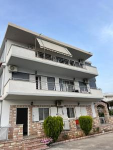 - un grand bâtiment blanc avec des balcons et des buissons dans l'établissement Guesthouse Butrinti, à Ksamil