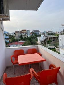 d'une table et de chaises rouges sur un balcon avec vue. dans l'établissement Guesthouse Butrinti, à Ksamil