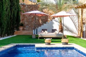 einen Hinterhof mit einem Pool mit Sonnenschirmen, einem Bett und einem Pool in der Unterkunft Cap Martinet Talamanca Vila Can Tashellu, Boutique 5 bed - Sea and Forest View in Talamanca