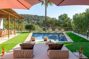 einem Tisch im Freien mit Stühlen und einem Sonnenschirm neben einem Pool in der Unterkunft Cap Martinet Talamanca Vila Can Tashellu, Boutique 5 bed - Sea and Forest View in Talamanca