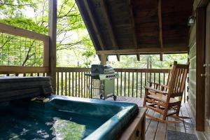 una vasca idromassaggio su una veranda con sedia a dondolo di Cozy Cabin! Hot Tub, King Bed, Fireplace, & Pool a Gatlinburg