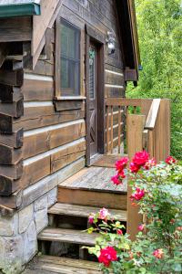 una cabina in legno con scala che conduce a una porta con fiori di Cozy Cabin! Hot Tub, King Bed, Fireplace, & Pool a Gatlinburg