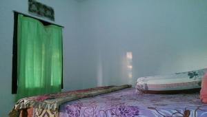 1 dormitorio con 1 cama y cortina verde en Diyah Homestay, en Kuta Lombok