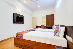 FabHotel GRK Comforts - Jayanagar في بانغالور: غرفة نوم بسريرين وتلفزيون بشاشة مسطحة