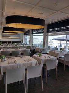 a dining room with white tables and white chairs at Hotel Sandeshoved Zeedijk in Nieuwpoort