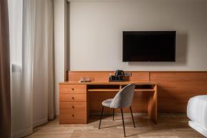 einen Schreibtisch mit Stuhl und einen TV an der Wand in der Unterkunft Hotel SB Express Tarragona in Tarragona