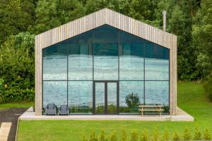 een glazen huis met 2 stoelen en een tafel bij Sete Cidades Lake Cabin - Casa da Lagoa in Ponta Delgada