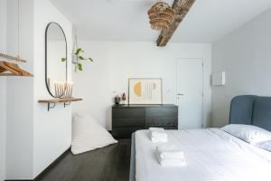 a white bedroom with a bed and a mirror at Chic Cityscape Apartment Ghent in Ghent