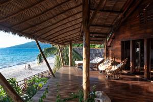 AmbolobozoShambala Madagascar: Beachfront Lodge And Adventures的海滩上带椅子和桌子的木制甲板