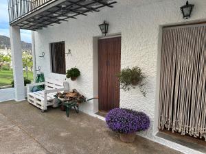 a porch of a white house with a bench and flowers at Las Vistas in Bubión