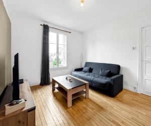 ein Wohnzimmer mit einem schwarzen Sofa und einem Couchtisch in der Unterkunft Élégant Pied-à-Terre à Beauvais in Beauvais